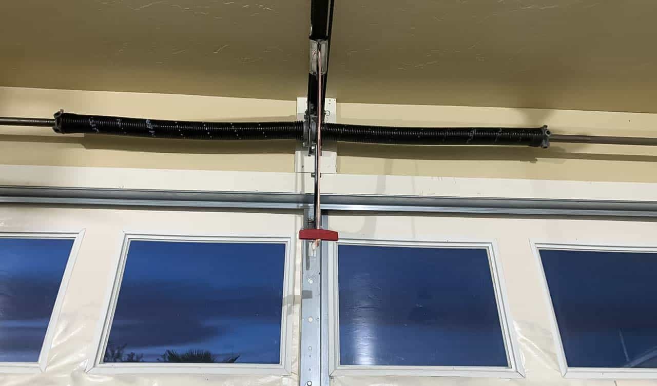Worn torsion spring above a residential garage door, close to failure
