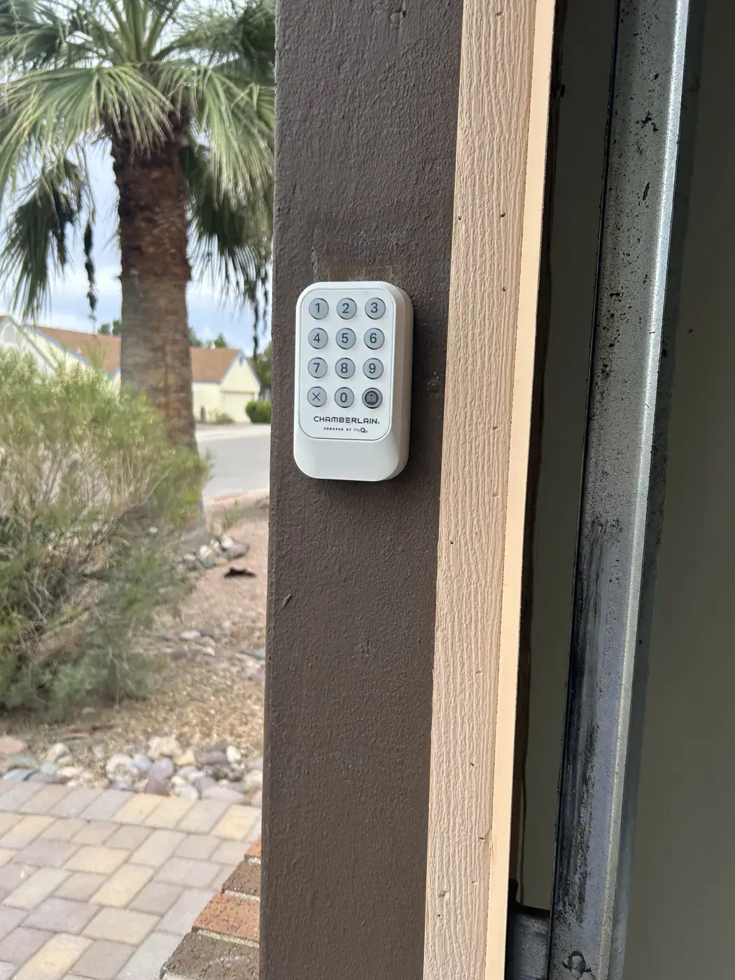 Wireless garage door keypad on a wood post beside a desert yard
