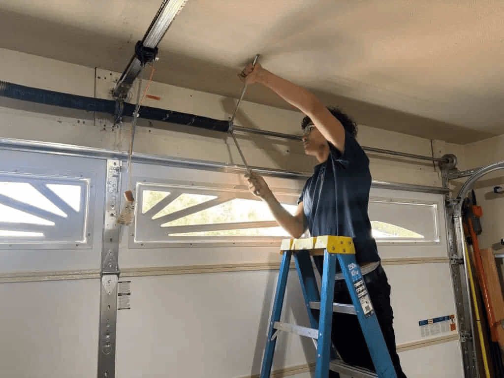 Discount Door Service technician winding a garage door torsion spring with a winding bar in a Tucson home garage