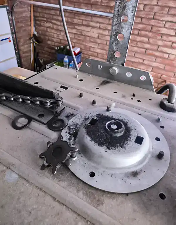 Failed gear and sprocket assembly on top of a garage door opener motor with the drive chain alongside, in Horizon Heights, Oro Valley