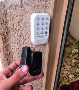 Chamberlain wireless garage door keypad installed beside a garage door in Rancho Vistoso, with two Chamberlain remotes