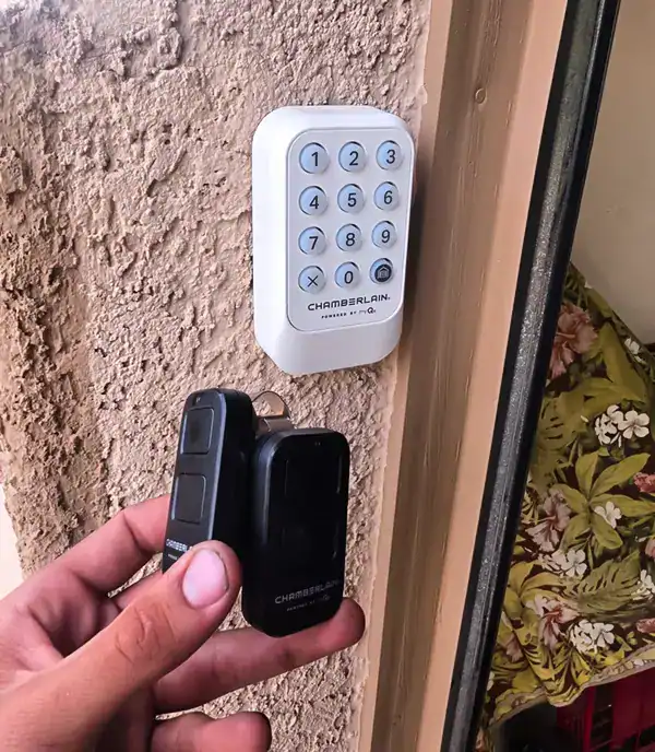 Chamberlain wireless garage door keypad installed beside a garage door in Rancho Vistoso, with two Chamberlain remotes
