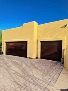 Two dark brown sectional garage doors on a yellow stucco home in Tucson, Arizona