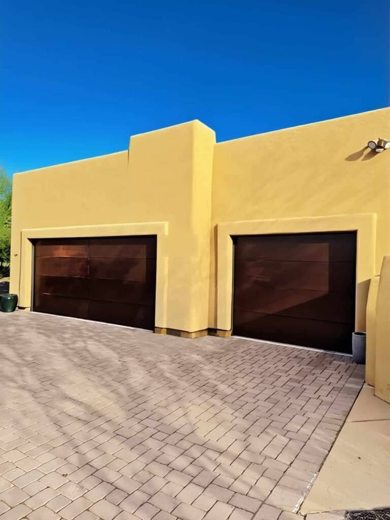 Two dark brown sectional garage doors on a yellow stucco home in Tucson, Arizona