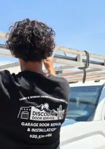 Discount Door Service technician in a branded shirt beside the service van at a garage door job in Gladden Farms, Marana