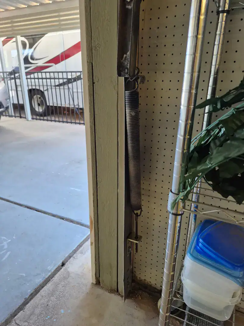 RV parked outside, seen past an extension spring on the garage door jamb