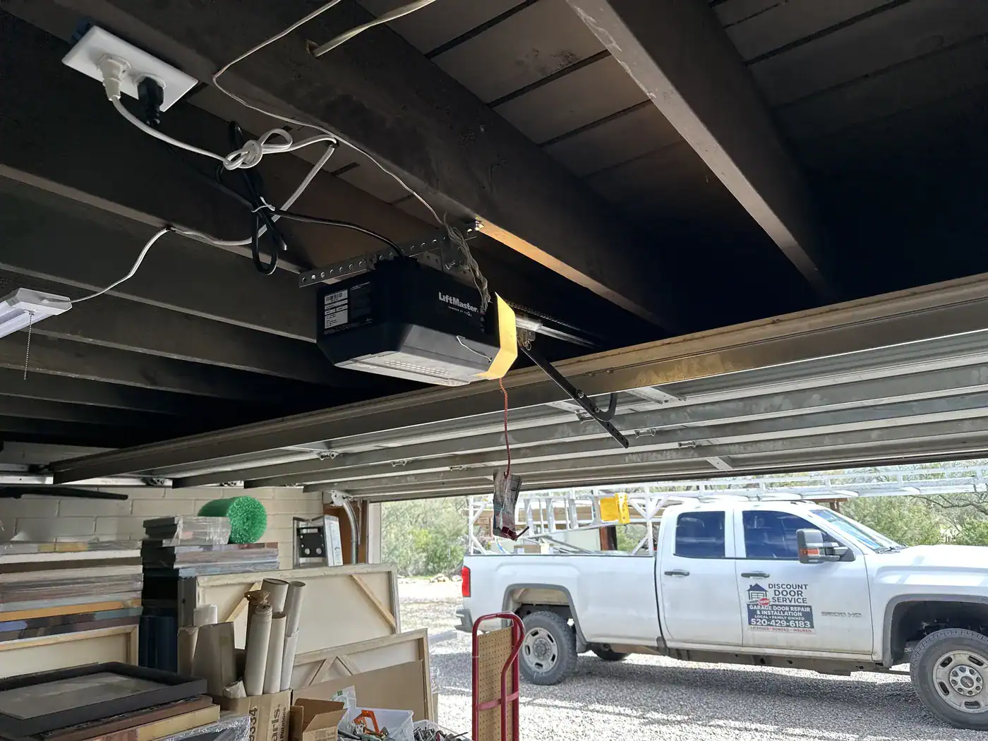 Discount Door Service truck outside, seen under a carport with an opener mounted to the beams
