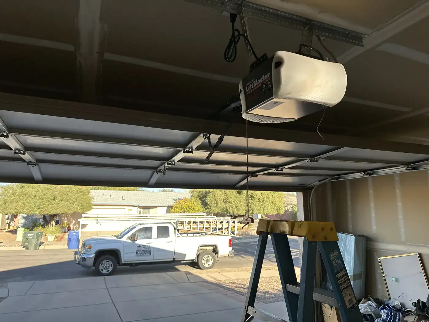 Service truck parked outside, seen from inside an open garage with the opener overhead