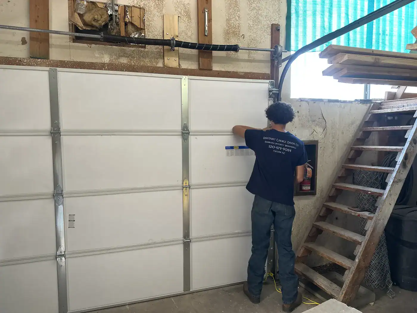 Discount Door Service technician fitting a new insulated garage door in a workshop