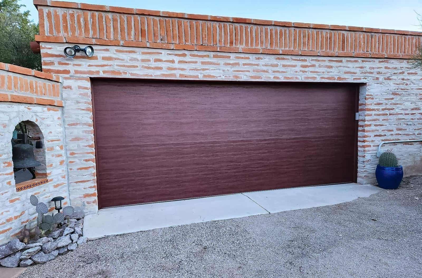 Dark wood-look garage door set in a brick wall on a Tucson home