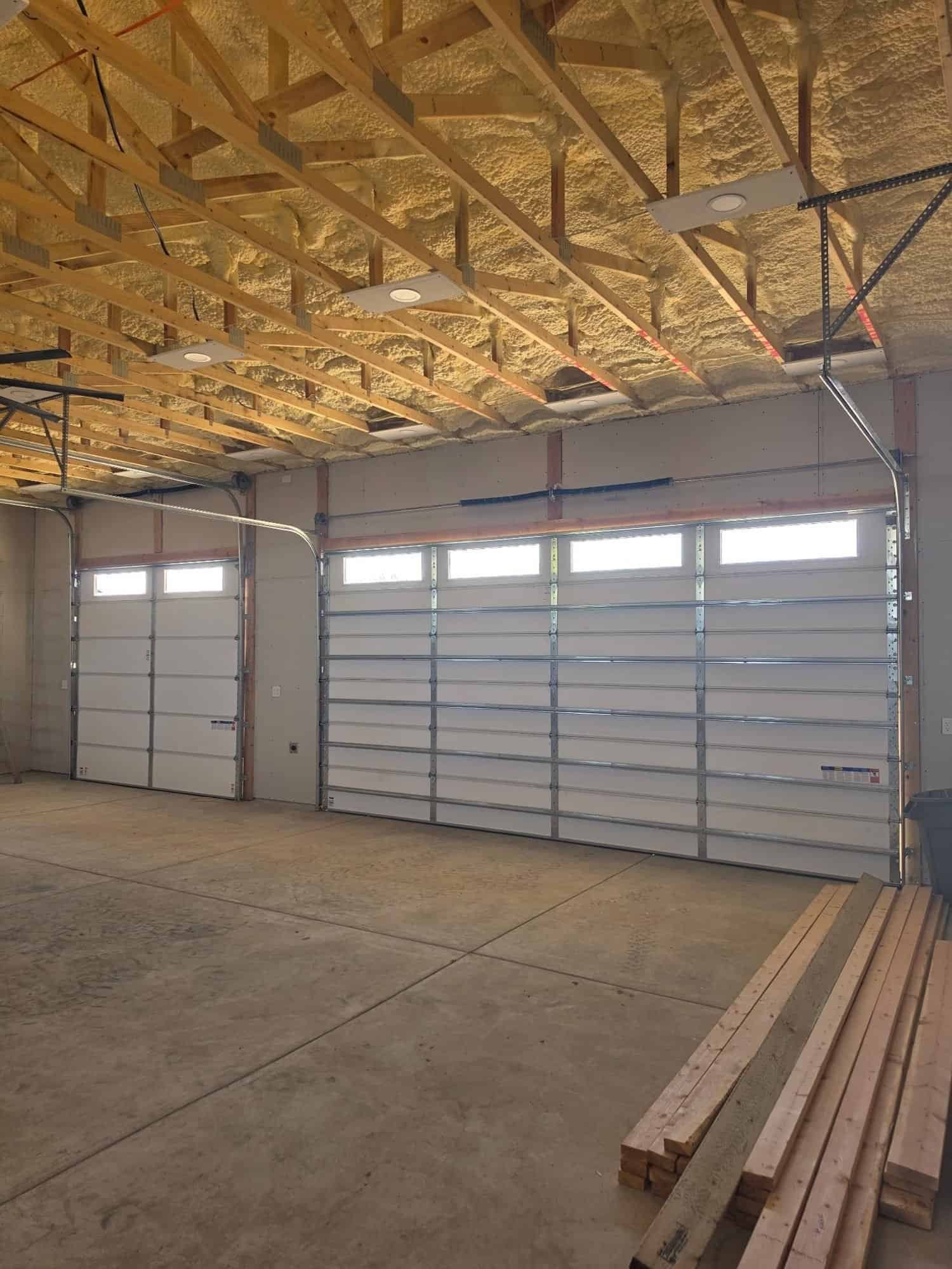 Inside of a large garage with sectional garage doors and a foam-sprayed ceiling above